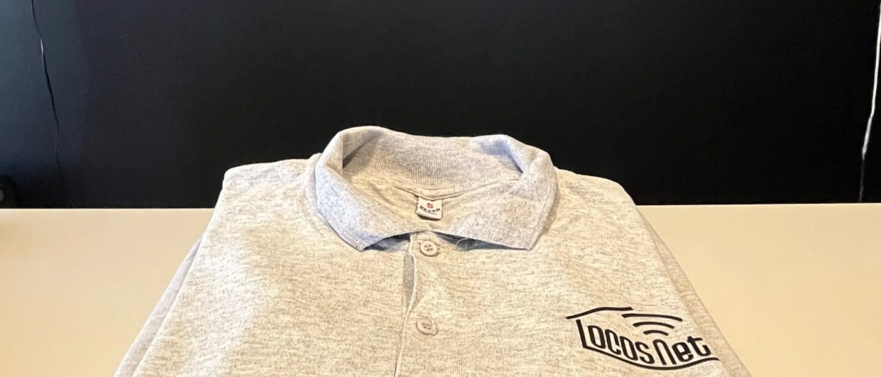 Chomba corporativa gris con logo aplicado de LocosNet, entrega real a cliente FOCUS+